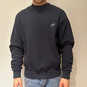 Marinblå sweatshirt från Eytys - Säljer en stilren marinblå/mörkblå sweatshirt från Eytys med deras logga broderad på bröstet. Tröjan har långa ärmar och ribbade muddar vid ärmslut och nederkant. Perfekt för en avslappnad look. Unisex - woman’s Large och mens M. Modellen är 180cm och 75kg. Mycket bra skick.