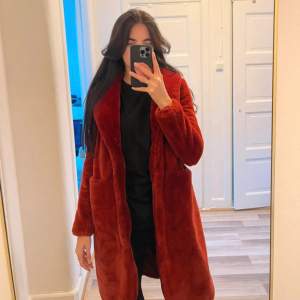 Säljer en mysig röd teddyjacka med lång ärm och normal passform. Perfekt för kyliga dagar och ger en trendig look. Jackan har en öppen design utan knappar eller dragkedja. 