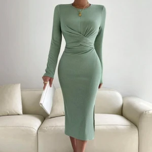 Grön långklänning med knyt - Elegant grön långklänning med långärmad design och knyt i midjan. Klänningen har en smickrande omlott-detalj framtill och en slits på sidan för extra stil. Perfekt för en chic look.