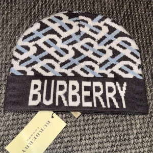 Burberry mössa - Snygg mössa från Burberry med ett stilrent mönster i svart, vitt och blått. Mössan har en bred kant med Burberry-loggan i vitt. Perfekt för att hålla sig varm med stil. Obs:skriv innan köp