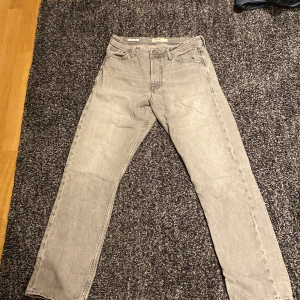 Grå jeans från Jack & Jones - Säljer ett par grå jeans från Jack & Jones i modellen Loose/Chris. De har en loose passform och är tillverkade i bomull. Perfekta för en avslappnad stil.