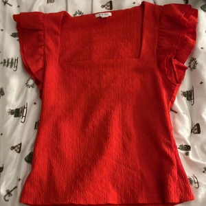 Fin röd topp - Använd 2 gånger, nyskick. Figursydd topp, ganska lång, går ner till höfterna. Liten i storlek, passar M/L.
