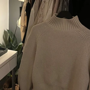 Beige stickad polotröja från h&m - Mysig beige stickad polotröja med ribbade detaljer. Perfekt för kyliga dagar med sin höga krage och långa ärmar. En stilren och bekväm tröja som passar till det mesta.