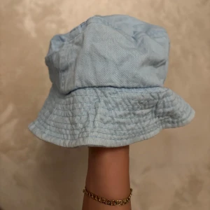 Ljusblå fiskehatt/buckethat - Snygg babyblå jeanshatt perfekt för sommardagar. Hatten har en avslappnad passform och är tillverkad i ett lätt och bekvämt material.