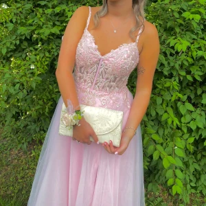 Rosa balklänning med spetsdetaljer - Jag säljer min älskade balklänning!!🩷 Elegant rosa balklänning med spetsdetaljer och smala axelband. Klänningen har en v-ringad urringning och en vacker snörning i ryggen. Den långa kjolen har en slits som ger extra rörelsefrihet. Klänningen är värd 5000kr!💕🩷 