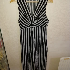 Svartvit randig klänning från KappAhl - Snygg svartvit randig klänning från KappAhl med v-ringning och knytning framtill. Perfekt för en stilren look.