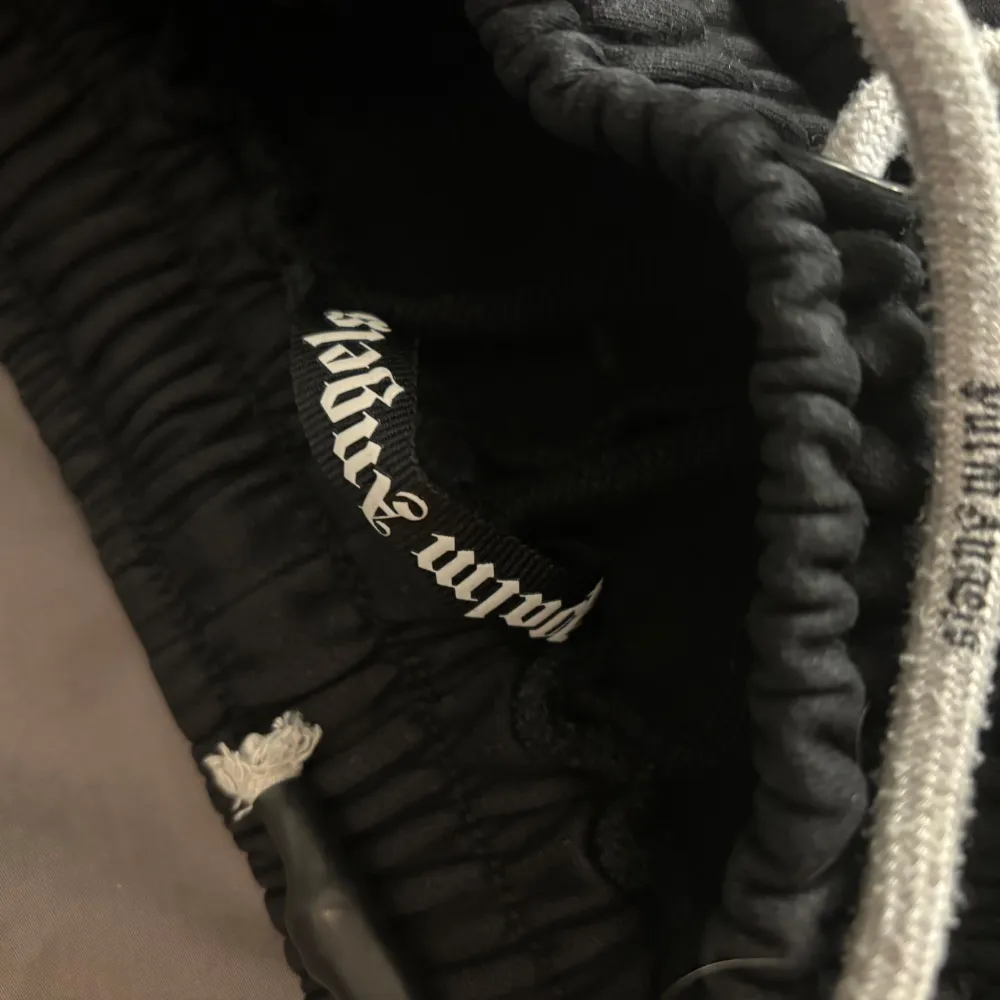 Snygga svarta mjukisbyxor från Palm Angels med vit logga framtill. Byxorna har en bekväm resårmidja med snörning för justerbar passform. Perfekta för en avslappnad stil. Väldigt lite använda, storlek small. Farkut & Housut.
