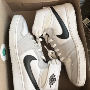 Nike Air Jordan 1 Retro AJKO Greyscale storlek 42,5 - Air Jordan 1 Retro AJKO Greyscale. Snygga Nike Air Jordans i vit canvas med svarta detaljer. Skorna har en klassisk hög design med snörning och den ikoniska Air jordan-loggan på skaftet. Orginalkartong.