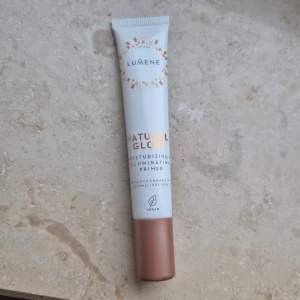Natural Glow Primer från Lumene - Moisturizing & Illuminating Primer från Lumene som ger en naturlig lyster. Förpackningen är vit med kopparfärgad kork och text i orange och svart. Vegansk och berikad med nordiska ingredienser. Jag har inte öppnat den eller använt den, jag fick den i min adventskalender men använder inte smink!