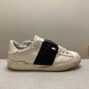 Valentino open( svarta ) - Snygga vita sneakers från Valentino med en iögonfallande svart detalj över snörningen. Skorna har en klassisk design med rund tå och platt sula. Perfekta för en stilren look.skicket är 5/10 man ser en defekt på sista bilden och de är även därför priset är så lågt. Har haft skorna i 3 år har tyvärr inte kvittot kvar men letar fortfarande efter kontoutdraget.
