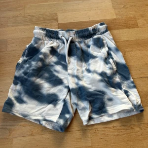 Blå och vita shorts med batikmönster - Snygga shorts i blått och vitt med batikmönster. De har en elastisk midja med snörning och praktiska sidofickor. Perfekta för en avslappnad stil. 💙 använd ett fåtal gånger