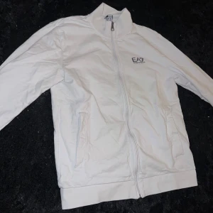 Vit ziptröja från EA7 Emporio Armani - Oanvänd, köpt från Zalando för 900. Haft hemma länge & har glömt den helt. Storlek M. Passar tjejer & killar.