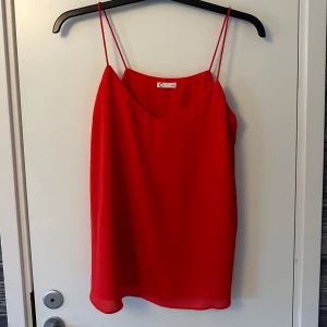 Röd linnetopp - Snygg röd linnetopp med tunna axelband och en luftig passform. Perfekt för varma sommardagar eller som ett lager under en kavaj. Enkel och stilren design som passar till många olika outfits.