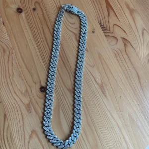 Glittrigt halsband i silver - Snyggt och glittrigt halsband i silver med en robust kedjedesign. Perfekt för att ge en extra touch av glamour till din outfit. Halsbandet har en säker låsmekanism som håller det på plats.pris kan diskuteras 