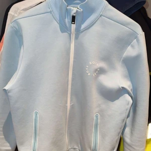 Ljusblå jacka från Boss - Snygg ljusblå jacka från Boss med dragkedja och ribbad krage. Jackan har två fickor med dragkedjor och en diskret logga på bröstet. Perfekt för en stilren look. Finns kvitto. Ny köpt för 2700. Pris kan diskuteras.