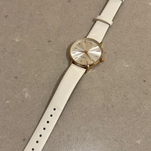 Vit klocka - Snygg och stilren vit klocka med roseguld/guld detaljer! Aldrig använd därav säljs den och är i nytt skick. Från märket ”Lucky Fox”. Uret tickar inte så mer för en snygg detalj på armen! Går att justera storleken efter önskan🩷