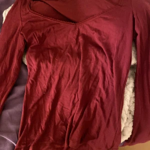 Vinröd topp från Nelly - Säljer en vinröd topp från Nelly med v-ringning och spetsdetaljer längs halsringningen. 