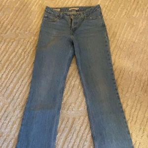 Blå jeans från Levi's - Säljer ett par klassiska blå jeans från Levi's. De har en straight passform och är lågmidjade, vilket ger en snygg siluett. Perfekta för en avslappnad stil.
