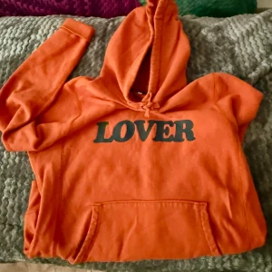 Lover hoodie från Bianca Chandôn - Säljer en cool orange hoodie från Bianca Chandôn med texten 'LOVER' i svart filt på framsidan, texturerat & nice print. Ett av deras fetaste Lover drops imo, färgen är otrolig irl. Perfekt för en avslappnad swag