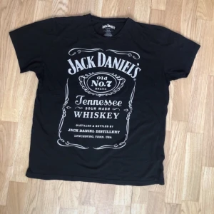 Svart Jack Daniel Printed T-Shirt  - Cool svart t-shirt från Jack Daniel's med det klassiska Old No. 7 Tennessee Whiskey-trycket i vitt. Perfekt för alla whiskeyälskare som vill ha en avslappnad stil. Tillverkad i mjuk bomull för extra komfort.
