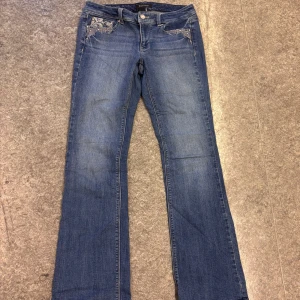 Blå bootcut jeans från White House Black Market - Snygga blå bootcut jeans med broderade detaljer på bakfickorna från White House Black Market. Perfekta för en avslappnad stil med en touch av elegans.