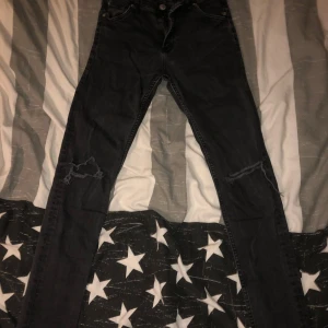 Svarta jeans med slitningar - Snygga svarta jeans med slitningar på knäna. De har en klassisk femficksdesign och knappar i midjan. Perfekta för en avslappnad stil.