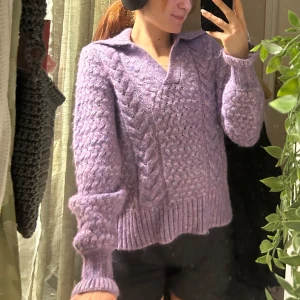 Lila stickad tröja  - Säljer en mysig lila stickad tröja från Y.A.S med kabelstickat mönster. Tröjan har en krage och långa ärmar, perfekt för kyliga dagar. Den är både stilren och bekväm.