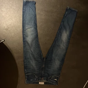 Blå jeans från lindebergh  - Snygga blå jeans från Lindex med klassisk femficksdesign och knappgylf. Perfekta för en avslappnad stil. De har en lätt tvättad look som ger en cool vibe.