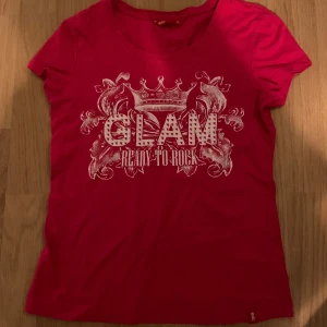Rosa t-shirt med tryck - Snygg rosa t-shirt med texten 'GLAM READY TO ROCK' i ett dekorativt tryck. Kortärmad och bekväm passform. Skriv privat vid frågor eller fler bilder, priset är diskuterbart!☺️