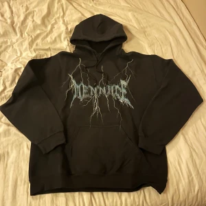 Svart hoodie med tryck - Cool svart hoodie med ett unikt tryck i blått och vitt framtill. Perfekt för en avslappnad stil med en stor ficka på magen och en bekväm huva. Passar bra till både jeans och joggers.