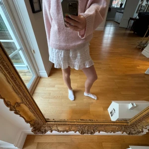 Vit kjol från Neo Noir - Söt vit kjol från Neo Noir med volangdetaljer och elastisk midja. Perfekt för en sommar dag. Kjolen har en kort längd och är tillverkad i ett lätt och luftigt material.