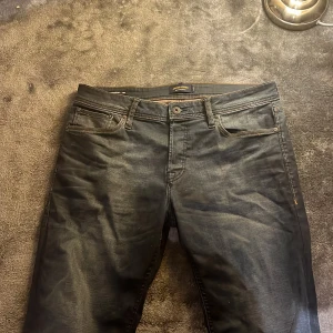 Mörk blå jeans från Jack & Jones - Snygga mörk blå jeans från Jack & Jones i modellen Slim Straight / Tim. De har en klassisk femficksdesign med knapp och dragkedja. Perfekta för en stilren look. Inte min stil längre därför säljer jag dom. Köpte dom för 899kr