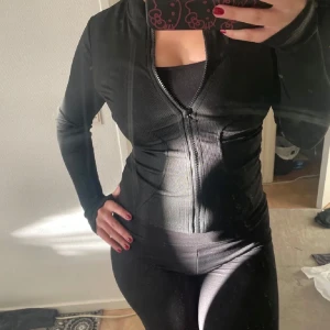 Svart ribbad hoodie - Snygg tränings kofta som används typ 2-3 ggr. Alltså i nyskick. Den är väldigt skön och stretchig, sitter åt så den framhäver kurvor 