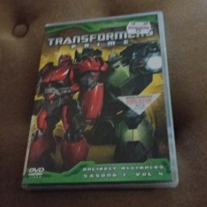 Transformers Animated: Season 1, Vol. 4 DVD - DVD med Transformers Animated, säsong 1, volym 4. Omslaget visar två robotar i rött och grönt mot en gul bakgrund. Perfekt för fans av animerade serier och robotar.