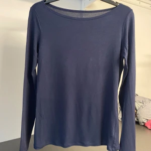 Mörkblå långärmad topp från Intimissimi - Säljer en stilren mörkblå långärmad topp från Intimissimi. Perfekt för en enkel och elegant look. Toppen har en rund halsringning och är tillverkad i ett mjukt material.