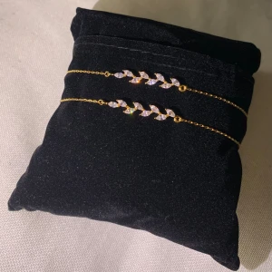 Silver armband - Elegant Guldpläterat silverarmband med glittriga stenar i ett lövmönster. Perfekt för att lägga till en touch av glamour till din stil. Armbanden har en fin kedja och säker låsning.