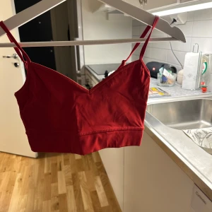 Röd topp - Snygg röd topp med smala axelband och v-ringad design. Perfekt för varma dagar eller som ett lager under andra plagg.