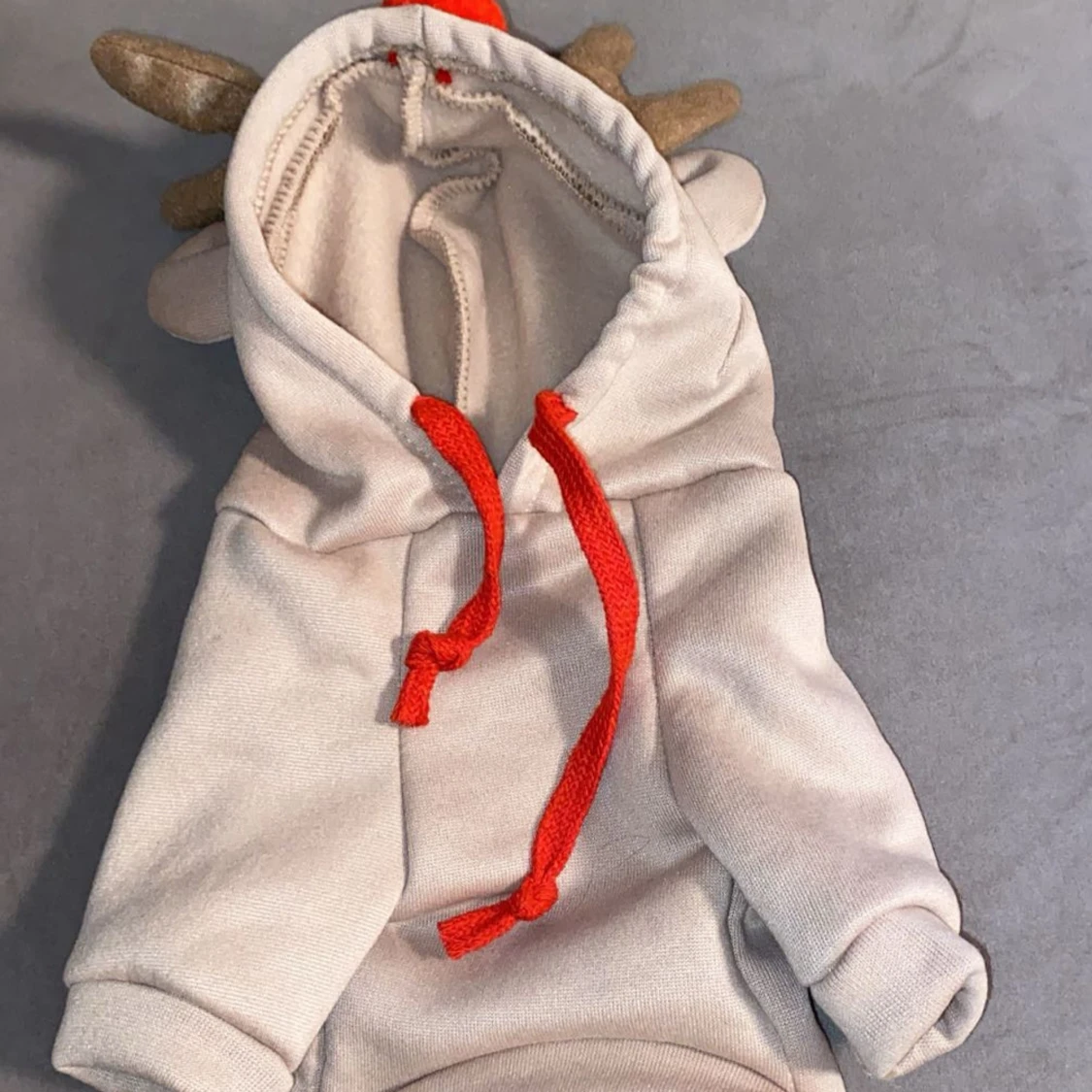 Beige huvtröja med horn och röda detaljer till hundar