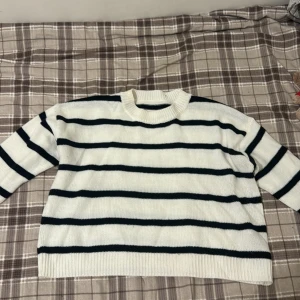 Vit och svart randig stickad tröja - Säljer en snygg vit stickad tröja med svarta ränder. Tröjan har en normal passform och långa ärmar, perfekt för kyligare dagar. Den är både stilren och bekväm, ett måste i garderoben! Kan vara lite kortare vid magen, använd några gånger och är från Shein, använd 5 gånger. Tröjan är i storlek S men är kort så kan kännas som XS