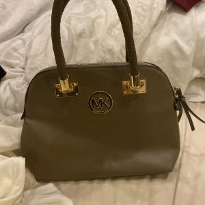 Brun handväska från Michael Kors - brun handväska från Michael Kors med flätade handtag och guldfärgade detaljer. Har inget bevis på att den är äkta, har fått den har knappt använt den