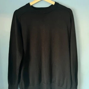 Svart tröja från H&M Edition - Säljer en snygg svart tröja från H&M Edition. Tröjan har en klassisk design med rund hals och långa ärmar. Perfekt för en minimalistisk look. Strl L men kan även passa M