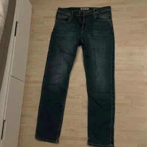 Blå jeans från Petrol Industries - Snygga blå jeans från Petrol Industries i regular fit. Klassisk design med fem fickor och knappgylf. Perfekta för en avslappnad stil.