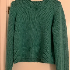Grön stickad tröja - Säljer en mysig grön stickad tröja med rund hals och långa ärmar. Perfekt för kyliga dagar och ger en skön och avslappnad stil. Passar bra till jeans eller kjol.