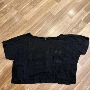 Svart croppad topp - En svart croppad topp med korta ärmar från Kappahl. Perfekt för en avslappnad stil. Toppen har en lös passform som är egentligen i storlek 159/164 men passar som S!