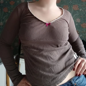 Brun långärmad topp från Odd Molly - Säljer en brun långärmad topp från Odd Molly med en söt rosa rosett vid halsringningen. Storlek 2 vilket motsvarar ungefär M🩷