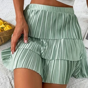Grön plisserad kjol - Snygg grön plisserad kortkjol med volangdetaljer. Perfekt för en somrig look. Kjolen har en elastisk midja för bekväm passform.