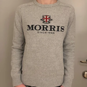 Morris tröja  - Säljer en stilren grå tröja från Morris med broderad logga och text 'Morris Since 1968' på framsidan. Tröjan har långa ärmar och ribbade muddar vid ärmslut och nederkant. Perfekt för en avslappnad och snygg look. Ny.