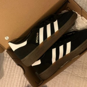 Adidas Handball Spezial i svart och vitt - Snygga Adidas Handball Spezial sneakers i svart med vita ränder och detaljer. Storlek 36 2/3. Aldrig använda då de är fel storlek. Glömde skicka tillbaka inom rätten för retur därav säljer jag dem. Nypris är 1279 på asos där jag köpte dem. 