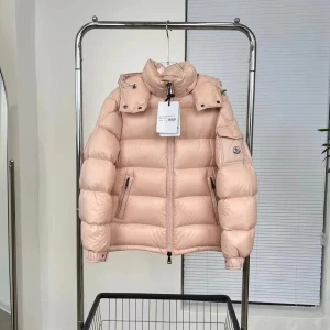 Ljusrosa dunjacka från Moncler - Snygg ljusrosa dunjacka från Moncler med avtagbar huva och dragkedja framtill. Jackan har en quiltad design och praktiska fickor med dragkedja. Perfekt för kyliga dagar.