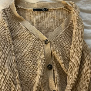 Beige stickad kofta från 157 - Säljer en mysig beige stickad kofta från 157. 🫶🏻☺️Koftan har en v-ringad design med knappar framtill och ribbade detaljer vid ärmslut och nederkant. Perfekt för lager-på-lager under kyliga dagar.🫶🏻Hör av er vid frågor☺️